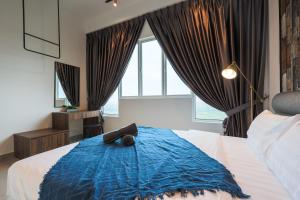 a bedroom with a large bed with a blue blanket at Amber Cove Melaka Icon stay in Melaka