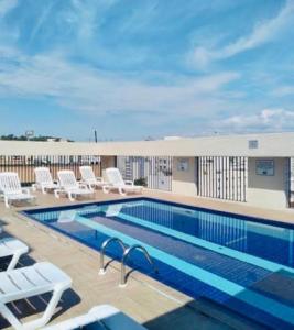 a pool on the roof of a building with white chairs at Flat Belvedere com piscina in São Vicente