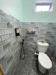 La salle de bains est pourvue de toilettes blanches et d'un mur en briques. dans l'établissement Homestay Naim Sabak Bernam, à Sabak Bernam