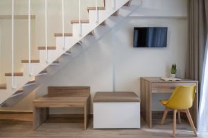 a living room with a staircase with a desk and a yellow chair at Aetherion Studios & Suites in Kalivia Poligirou