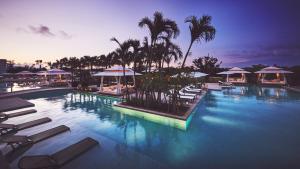 a large swimming pool with lounge chairs and palm trees at ANA InterContinental Ishigaki Resort by IHG in Ishigaki Island