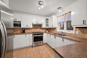 een keuken met witte kasten en roestvrijstalen apparatuur bij Private Oasis for Ultimate Relaxation in Montreal