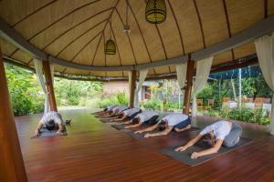 un gruppo di persone che fa una posa yoga in una stanza di De Moksha Eco Friendly Boutique Resort a Tanah Lot Altre 32 foto