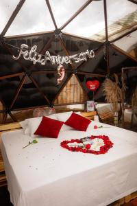 a bed with red flowers on it in a tent at Happy Glamping Quindio - Tipo Domo Traslúcido in Calarcá +42 photos
