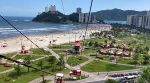 a gondola ride over a beach with people at Flat Belvedere com piscina in São Vicente