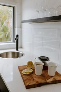 a cutting board with two cups of tea and lemons on a kitchen counter at Yeppoon Surfside Motel in Yeppoon