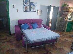 a bed in a room with a purple couch at Almajar 4 in El Puerto de Santa María