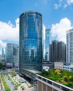 un grand bâtiment en verre dans une ville avec de grands bâtiments dans l'établissement Huaqiang Plaza Hotel Shenzhen, Enjoy Complimentary Afternoon Tea & Mini Bar & Night Snack, à Shenzhen