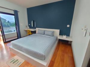 um quarto com uma cama grande e uma parede azul em โรงแรมดีดีธาราอิน - DD tara inn em Uttaradit