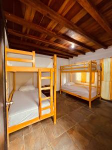 Onda Hostel Mompiche في مومبيش: سريرين بطابقين في غرفة ذات سقوف خشبية