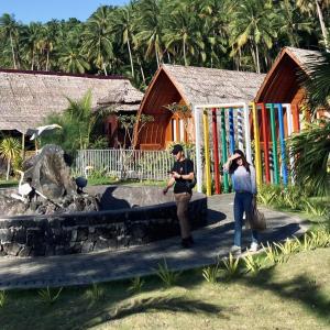 zwei Personen stehen vor einem Gebäude mit einem Brunnen in der Unterkunft Wailanga Resort in Ternate