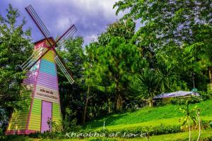 un moulin à vent coloré sur une colline verdoyante plantée d'arbres dans l'établissement เขาค้อออฟเลิฟ, à Khao Kho