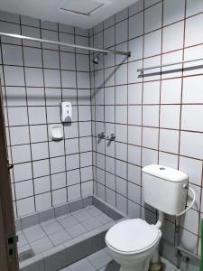 a white tiled bathroom with a toilet and a shower at Faber Inn in Bintulu