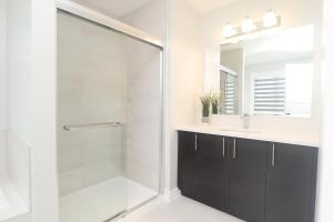 a bathroom with a glass shower and a sink at Tranquil Nest By The Airport in Ottawa
