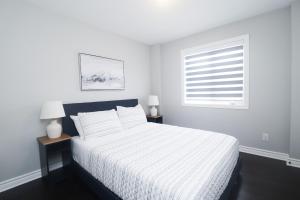 a white bedroom with a bed and a window at Tranquil Nest By The Airport in Ottawa