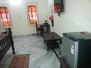 a living room with a table and a refrigerator at Palace Fresco in Jhunjhunūn