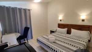 a bedroom with two beds and a chair in it at Destination Inn Cache Creek in Cache Creek