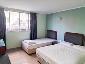 een slaapkamer met 2 bedden en een raam bij Faber Inn in Bintulu