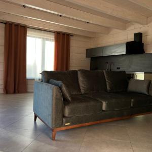 Sofá marrón en la sala de estar con ventana en Chalet PidStromom en Mykulychyn