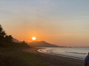 um pôr do sol numa praia com uma montanha ao fundo em B@B Omaherma Home stay em Boras