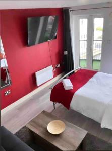 a red bedroom with a bed with a red wall at Entire Flat with balcony in London