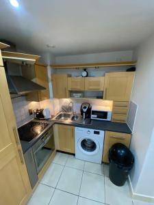 a small kitchen with a sink and a washing machine at Entire Flat with balcony in London