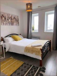 a bedroom with a bed with white sheets and yellow pillows at Entire Flat with balcony in London