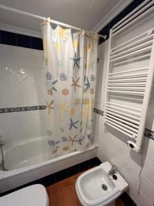 y baño con aseo, lavamanos y cortina de ducha. en COSTA MARIÑA Fabuloso apartamento en la costa, en O Vicedo