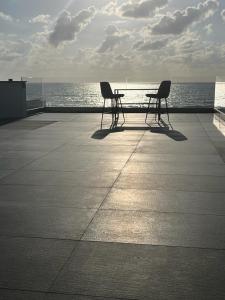 dos sillas y una mesa sentada en un paseo cerca del océano en מלון בוטיק H34, en Nahariyya