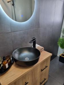 a bathroom with a black sink on a wooden vanity at La Cetate Luxury Apartment in Ipoteşti