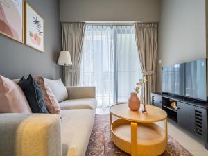 Una sala de estar con un sofá, un televisor y una mesa. en Business Bay's Coziest Hideaway With Balcony, en Dubái