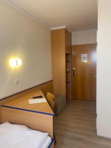 Habitación con cama, escritorio y puerta. en REGIOHOTEL Salzland Schönebeck 