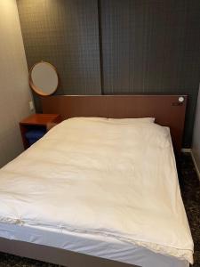 Bett in einem Zimmer mit weißem Bettlaken in der Unterkunft 玉出202 wifi付 玉出駅から徒歩2分 地下鉄難波迄8分 in Osaka