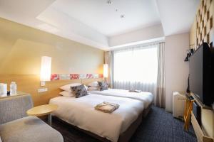 a hotel room with two beds and a flat screen tv at Hotel Grand Bach Kyoto Select in Kyoto