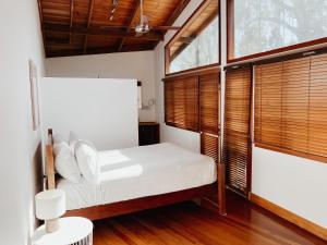 a bedroom with a white bed and windows at Bellingdale Farm in Clothiers Creek