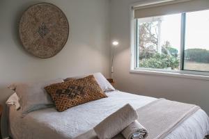 a bedroom with a bed with two pillows and a window at Daybreak Mollymook in Mollymook