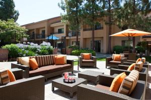 un patio con sofás, mesas y una sombrilla en Courtyard by Marriott Pleasanton en Pleasanton