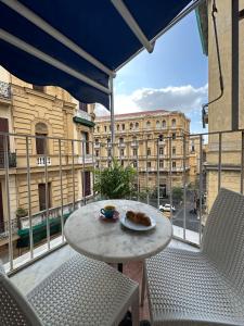 un tavolo e sedie su un balcone con vista su un edificio di B&B Quattro Palazzi Napoli Centro a Napoli