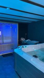 ein großes Bad mit einer Badewanne und einem Fenster in der Unterkunft Casawellness améthyste ou jaspe océan avec jacuzzi intérieur in Floreffe