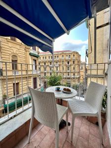 un patio con 2 sillas y una mesa en el balcón en B&B Quattro Palazzi Napoli Centro, en Nápoles