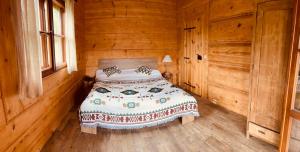 ein Schlafzimmer mit einem Bett in einer Holzhütte in der Unterkunft Wilk u Drzwi in Ustrzyki Dolne