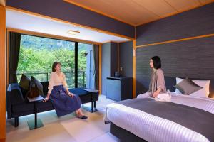 Duas mulheres estão sentadas num quarto com uma cama. em TAOYA Nasu Shiobara em Nasushiobara