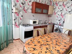 kuchnia ze stołem, kuchenką i kuchenką mikrofalową w obiekcie Апартаменты с 2 спальнями w mieście Atyrau