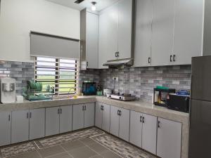 a kitchen with white cabinets and a sink at Villa De Lova - Wakaf Che Yeh in Kota Bharu