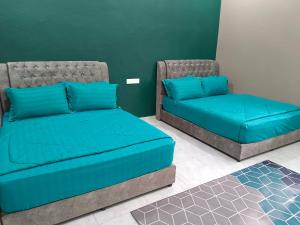 two beds with blue pillows in a room at Villa De Lova - Wakaf Che Yeh in Kota Bharu