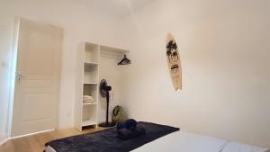 1 dormitorio con cama y tabla de surf en la pared en La remise des Copains 2 chambres avec Clim OcKeys, en Limoux