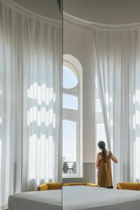 a woman standing in a bedroom looking out the window at Casa Alberola Alicante, Curio Collection By Hilton in Alicante