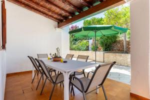 ein Esszimmer mit einem Tisch und einem grünen Sonnenschirm in der Unterkunft Villa Can Joan den Coves in Santa Gertrudis