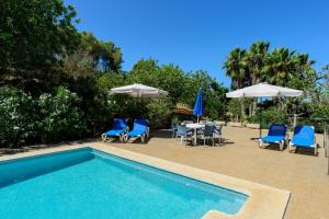 una piscina con sillas, mesas y sombrillas en Villa Can Joan den Coves en Santa Gertrudis