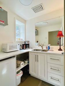 cocina con armarios blancos, fregadero y lámpara roja en Waterfront Room1 with Private Bath near Marina, en Gibsons